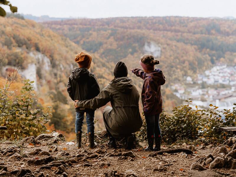 Mutter mit ihren beiden Kindern im Herbst mit Laub