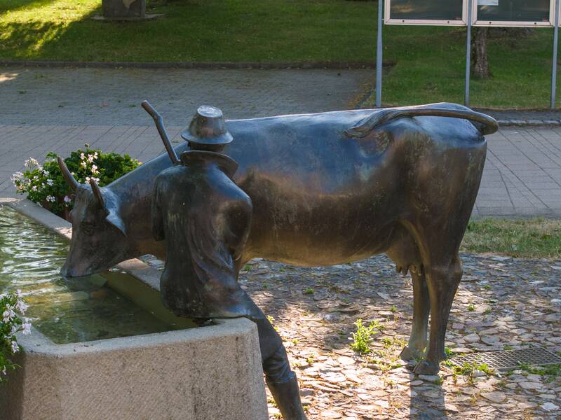 Ein Brunnen mit Kuh und Hirte